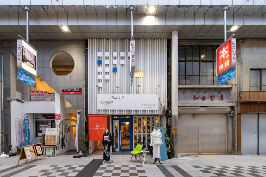 商店街に面したUTAKATA HOTEL HIMEJIの店頭。赤い暖簾と青い扉