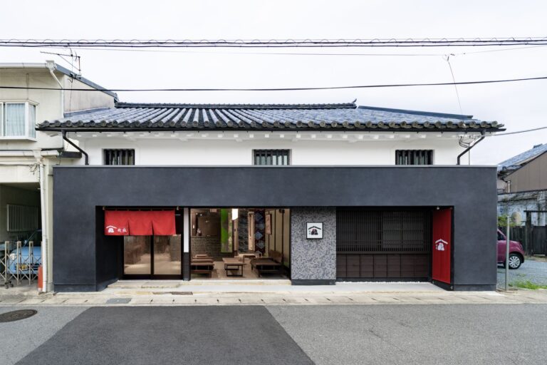 古民家旅館 侘寂の外観。黒漆喰の壁に赤い暖簾と瓦屋根